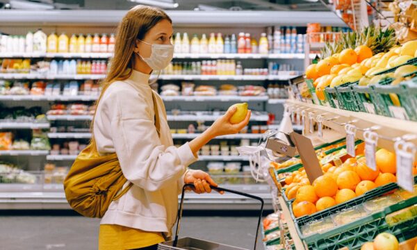 Woman in Yellow Tshirt and Beige jacket Holding a Fruit Stand